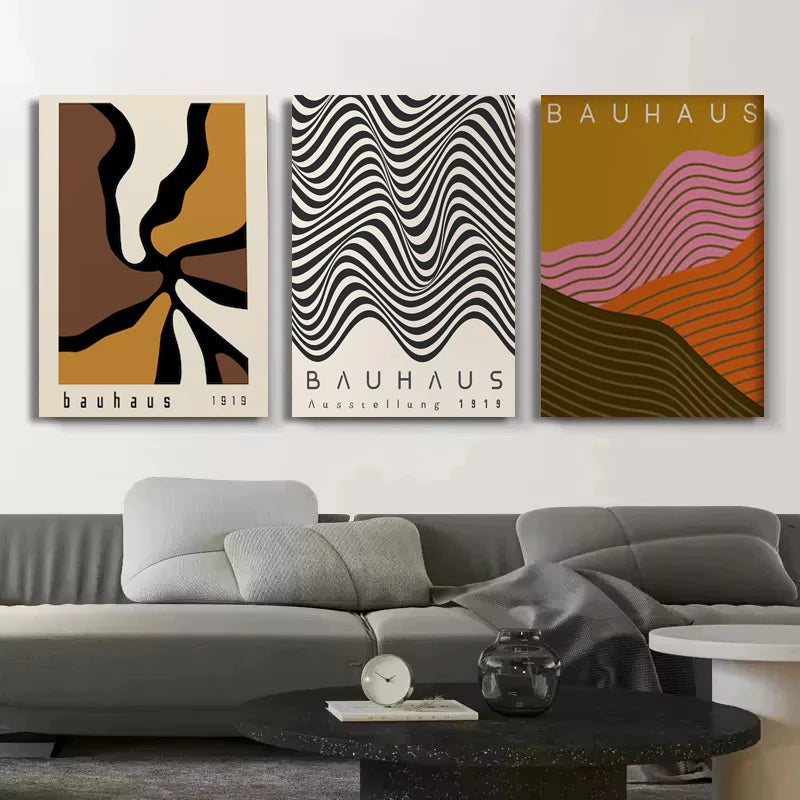Three Bauhaus-style posters on a wall above a modern grey sofa.
