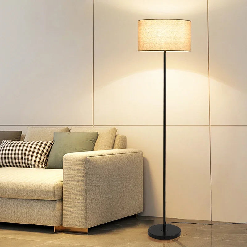 Full view of the minimalist Black Floor Lamp with a lit beige fabric shade.