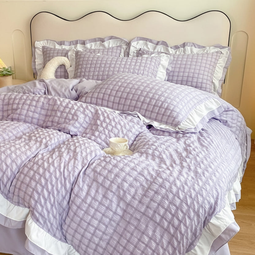 Purple checkered duvet set with ruffled edges on a bed in a bedroom setting.