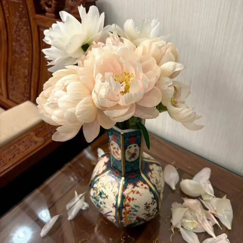 Decorative vase with white and light pink flowers on a reflective surface