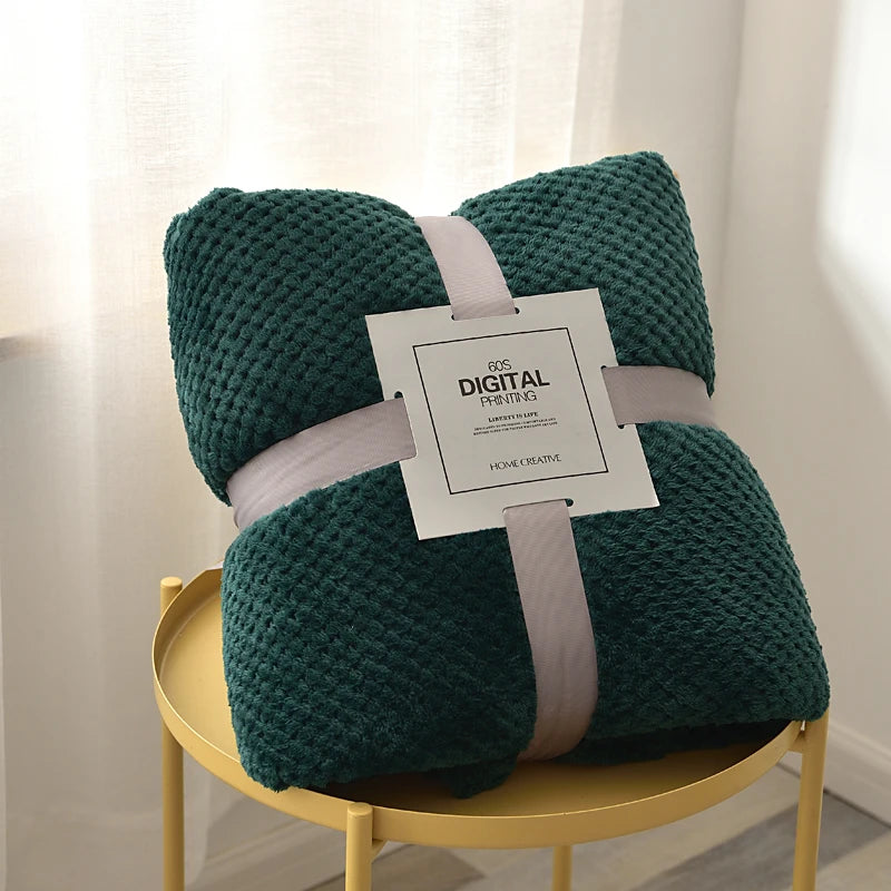 Green textured blanket with a tag on a yellow stool against a light curtain background