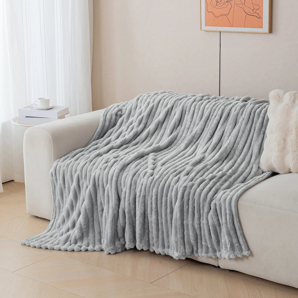 Charcoal grey blanket draped over a white sofa in a living room setting.