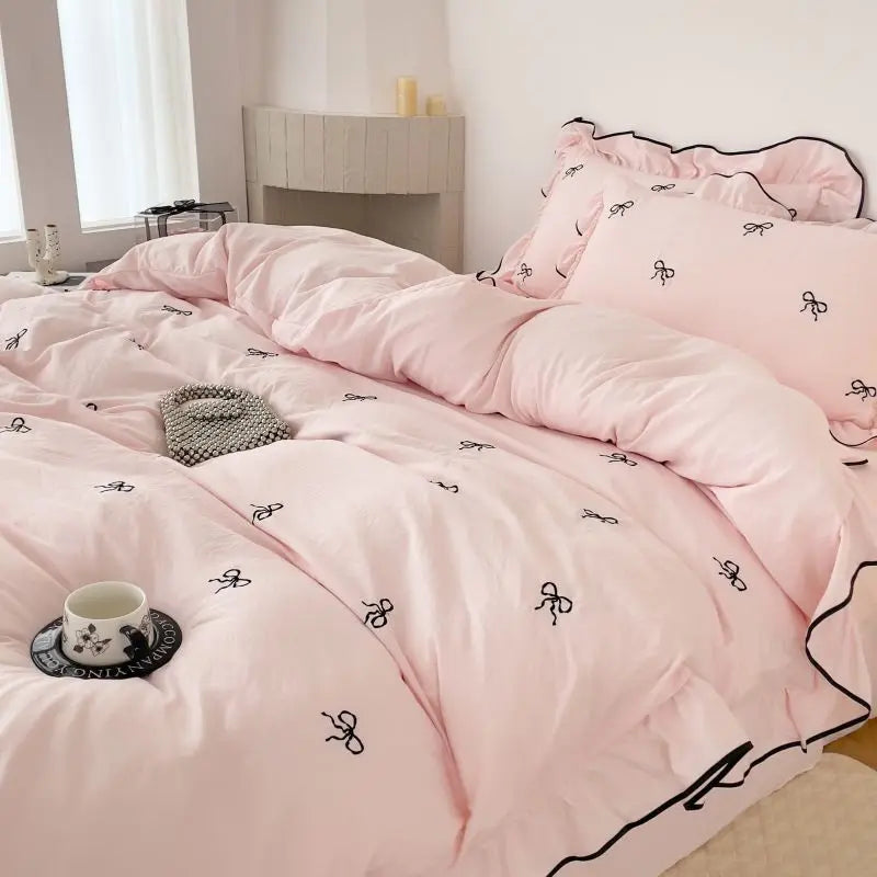 Wide shot of the Soft Blush duvet set on a bed, showcasing the repeating bow pattern and romantic ruffles in a bright, airy room.