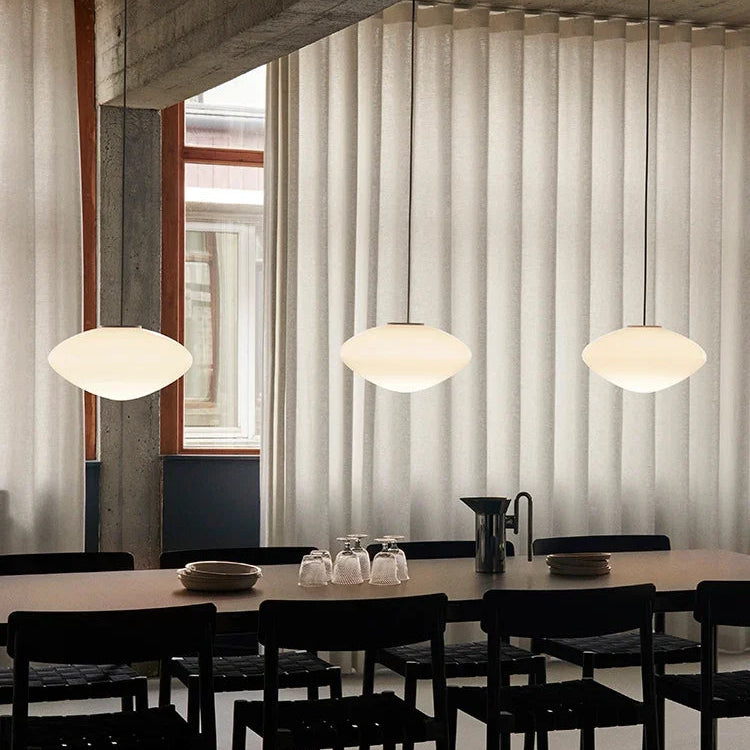 Modern dining room with a long table, chairs, and pendant lights.