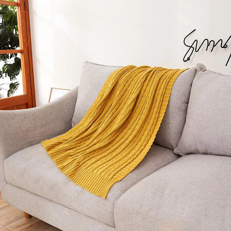 Yellow blanket draped over a gray sofa in a living room setting.