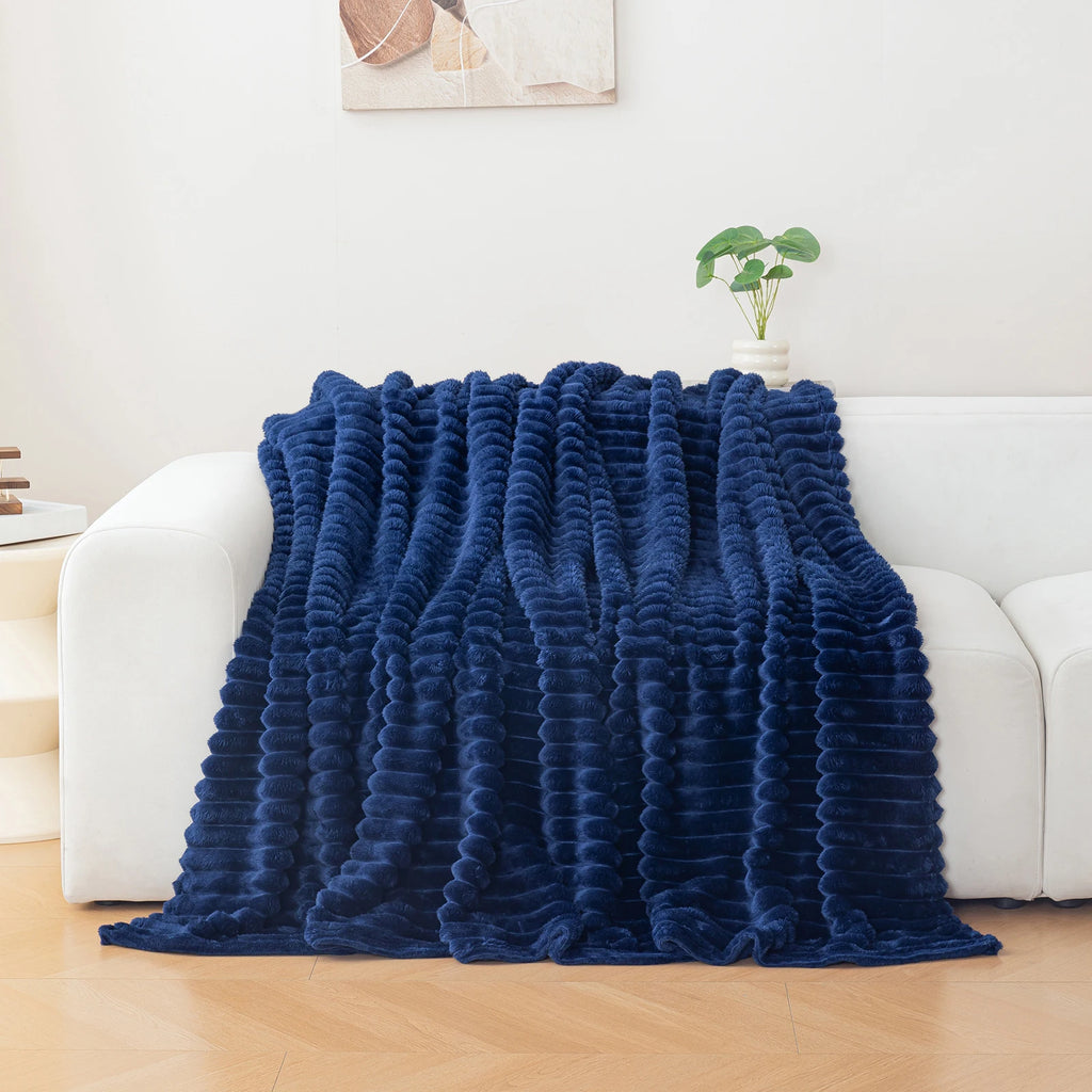 Navy blue textured blanket draped over a white sofa in a living room setting.