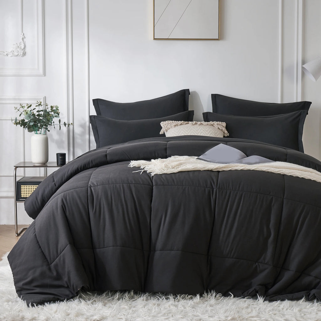 Black comforter set on a bed in a bedroom with white walls and decor.