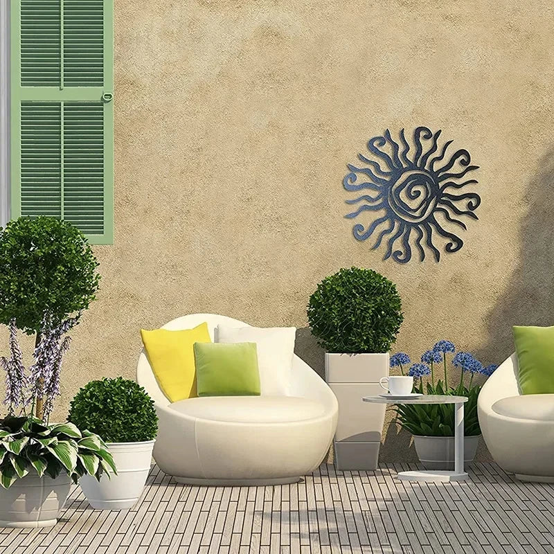 Outdoor seating area with white chairs, green and yellow cushions, potted plants, and a sun-shaped wall art on a beige wall.
