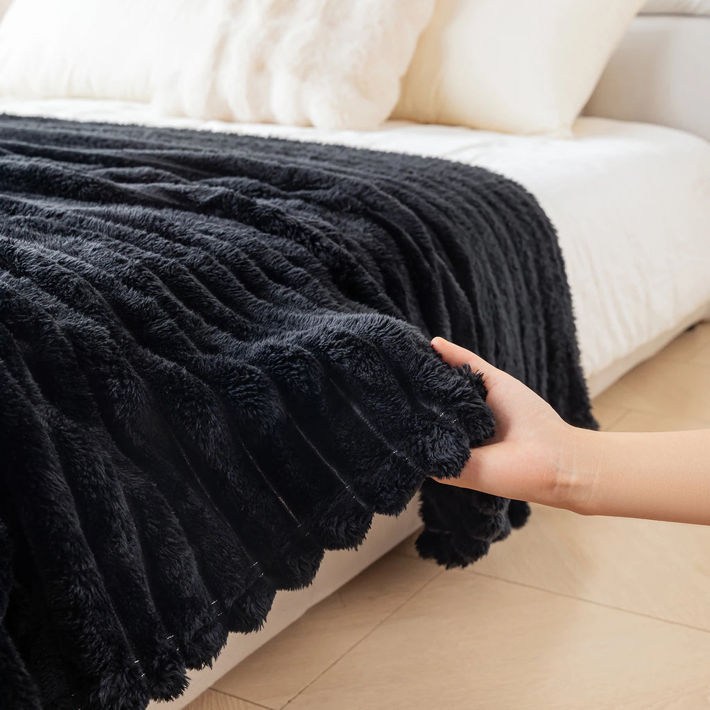 Black textured blanket being held over a white sofa