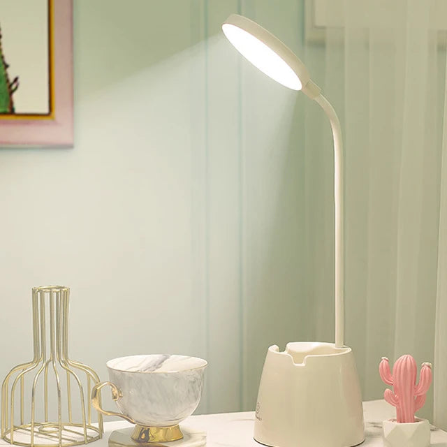 White LED desk lamp on a surface with decorative items in a room setting