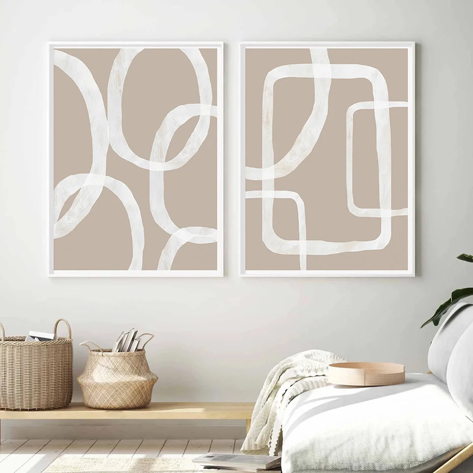 Two abstract wall art pieces on a white wall with a shelf and decor items below.