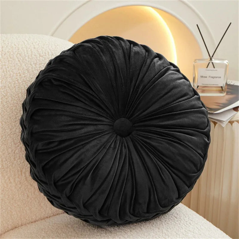 Black round cushion on a beige sofa with a blurred background