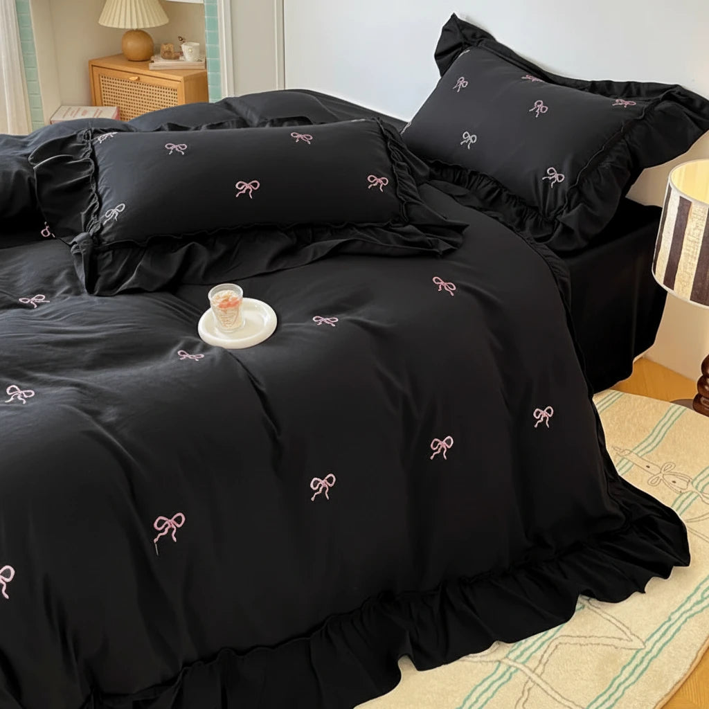 Black bedspread with bow patterns on a bed in a bedroom setting.