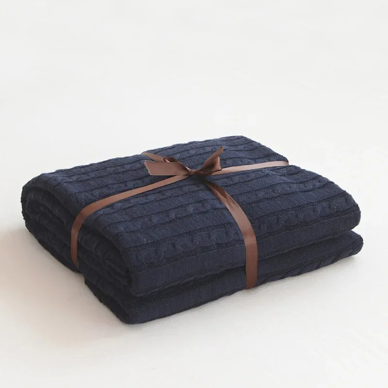 Folded navy blue blanket with a brown ribbon on a white background