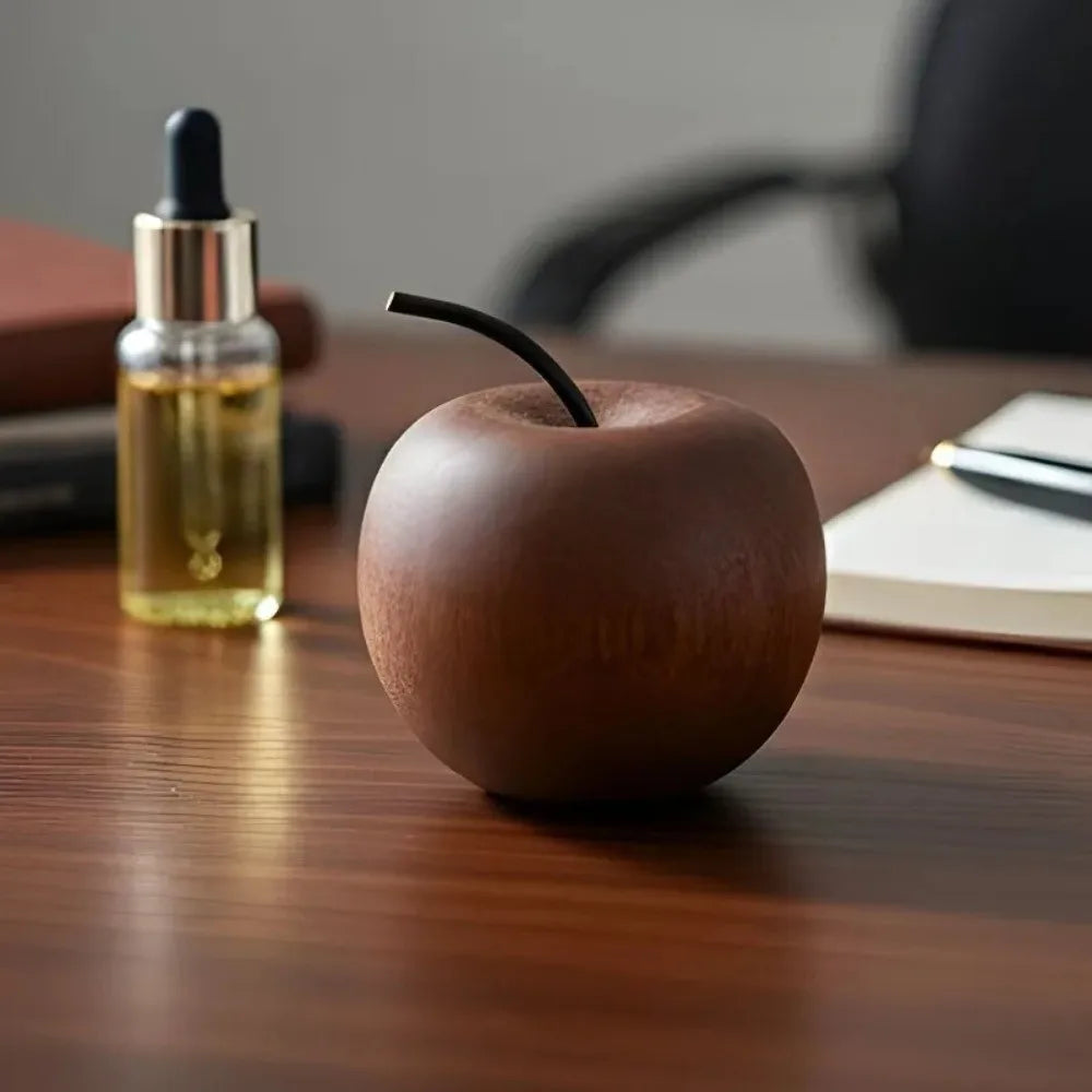 Wooden apple shaped oil diffuser on a wooden surface with blurred background