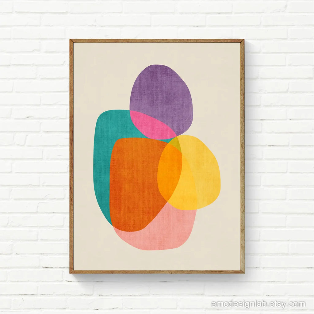 Framed abstract art print with colorful shapes on a white brick wall