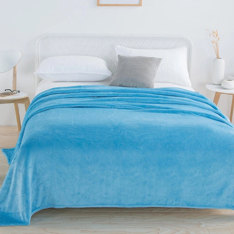 Sky blue plush blanket on a bed with a grey cushion