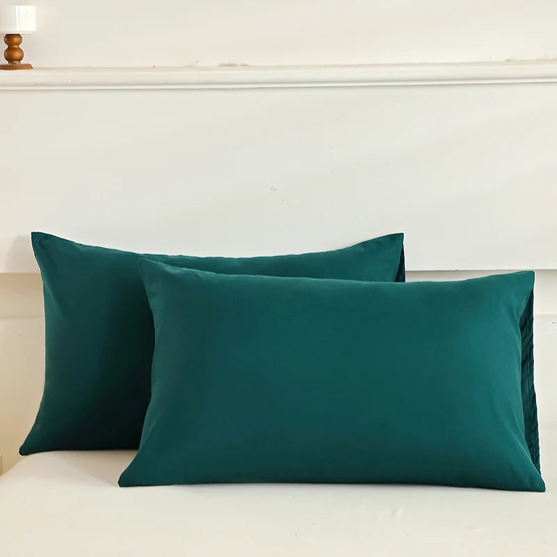 Two green pillows on a bed with a neutral headboard.