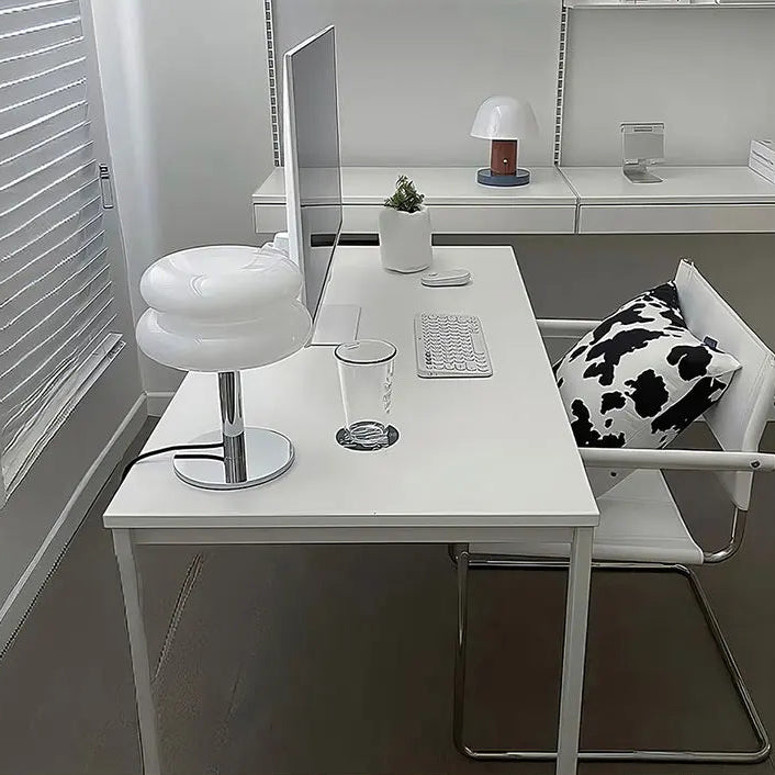 Modern office desk setup with a chair, a white table lamp, and a computer monitor.