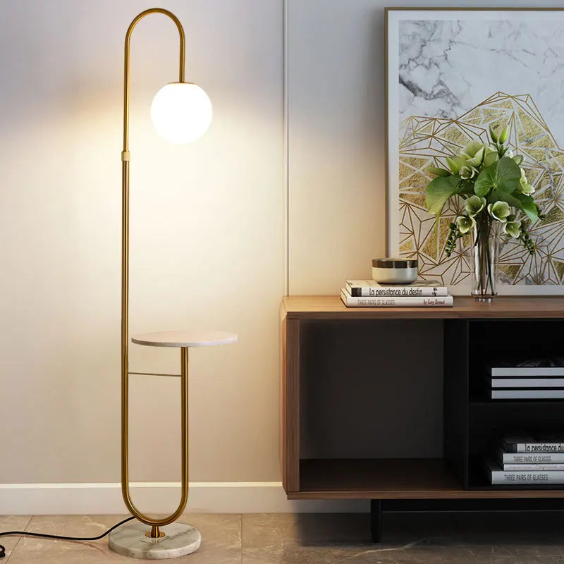 A gold floor lamp styled next to a console table