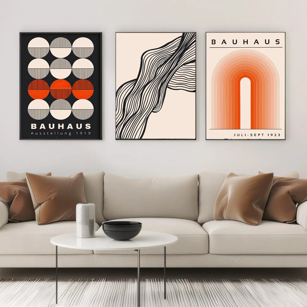 Three Bauhaus style posters on a wall above a beige sofa.