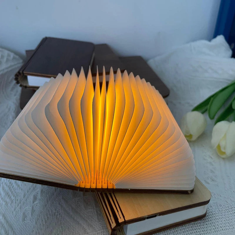 Open book with glowing pages on a white surface with tulips