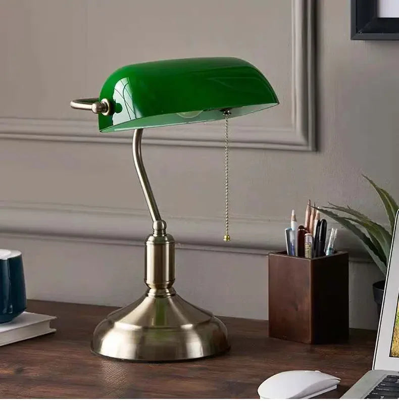 Green glass banker-style desktop lamp with antique brass metal base and pull-chain detail