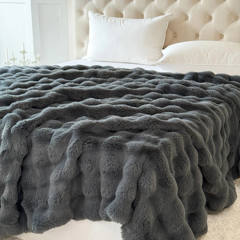 A charcoal-textured blanket on a bed with a tufted headboard