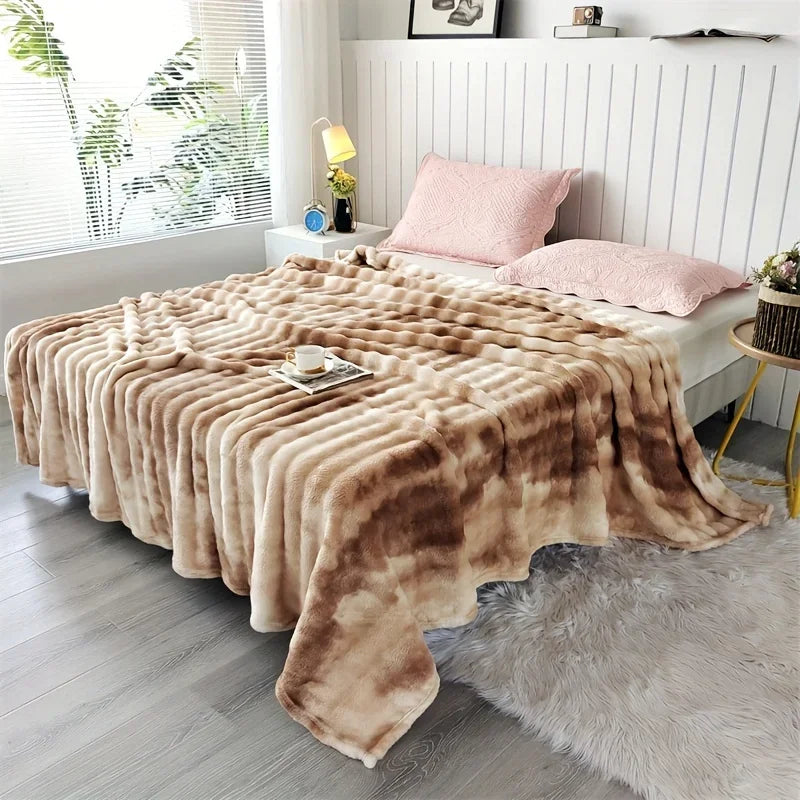 A Beige tie dye blanket draped over a bed in a bedroom setting with pillows and decor.