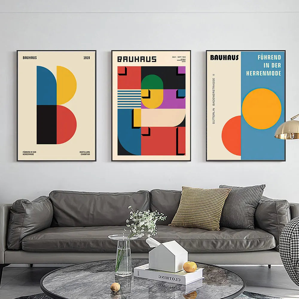 Modern living room with gray sofa and three colorful Bauhaus-style posters on the wall.