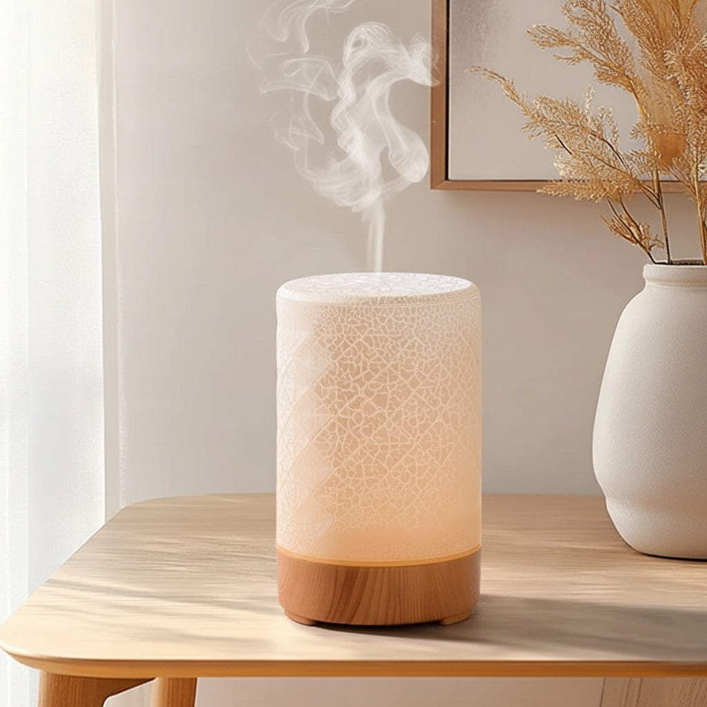 A diffuser emitting steam on a wooden table with a vase in the background.