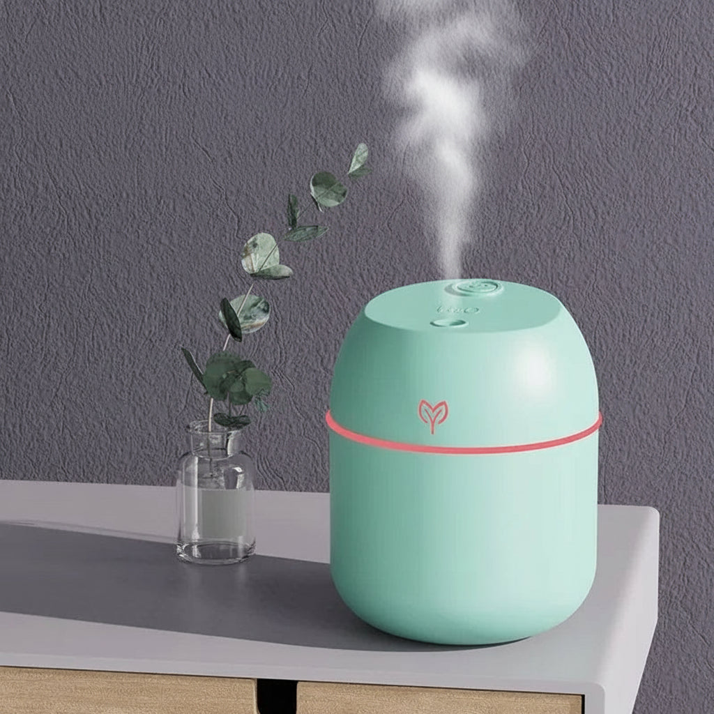 Mint green humidifier with pink accent on a table with a gray wall background