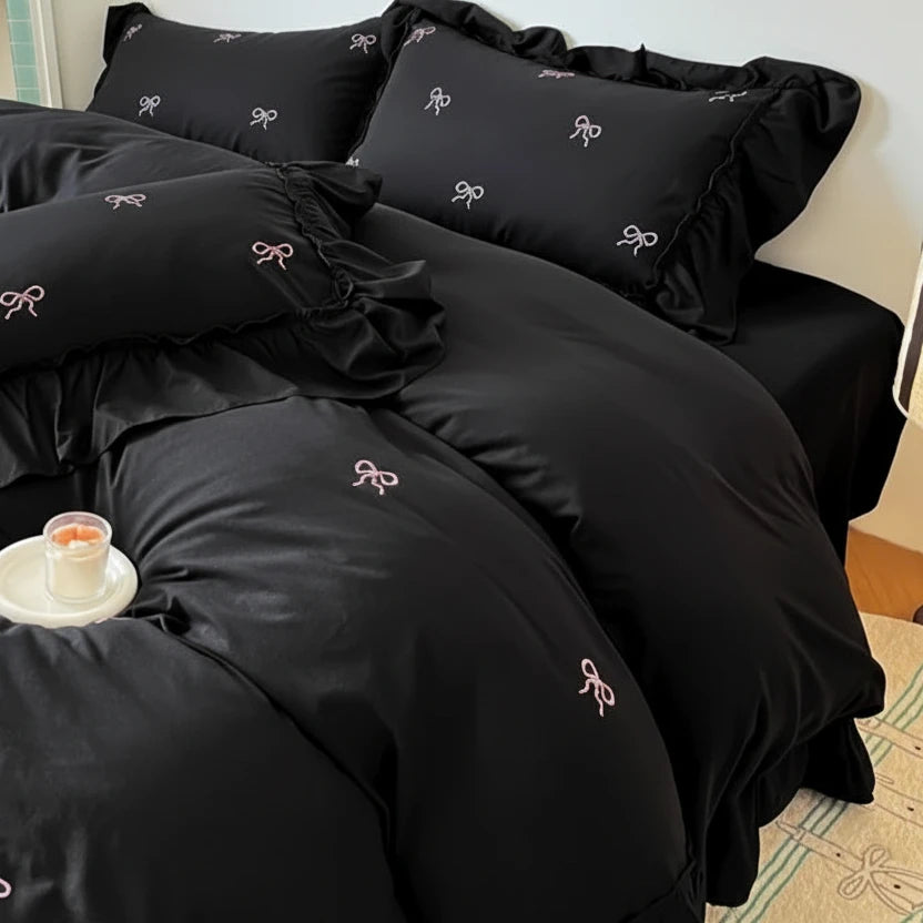 Black bedding set with bow patterns on a bed.