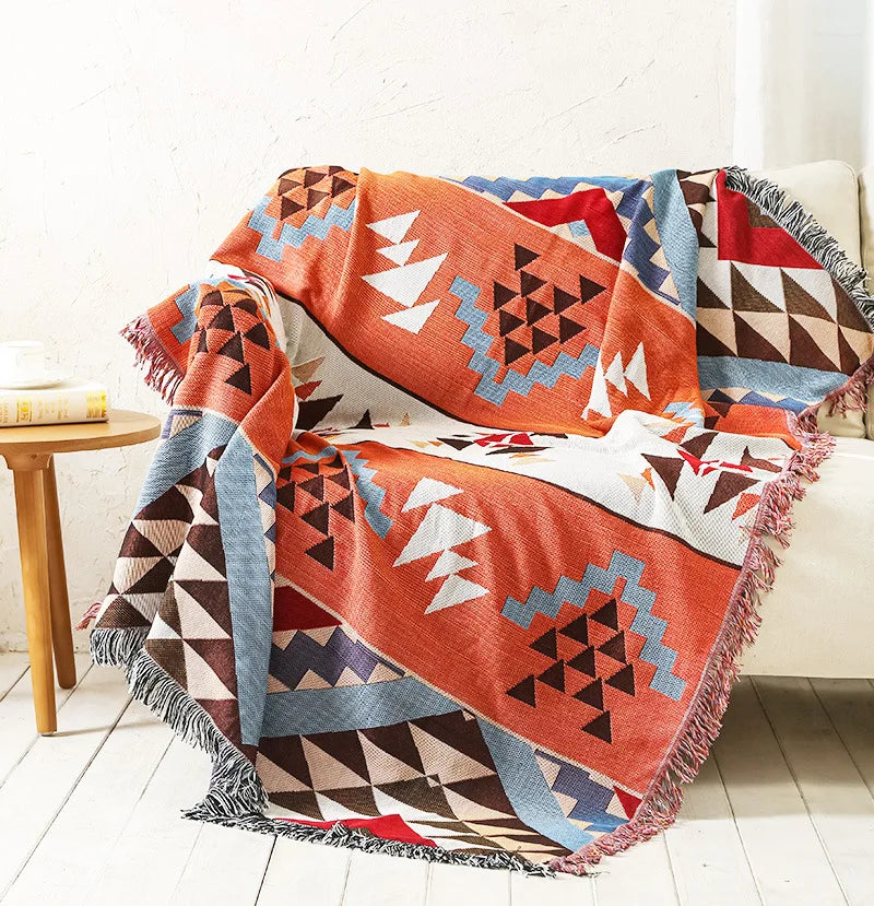 Bohemian sofa throw featuring vibrant orange and red triangular patterns with blue accents.