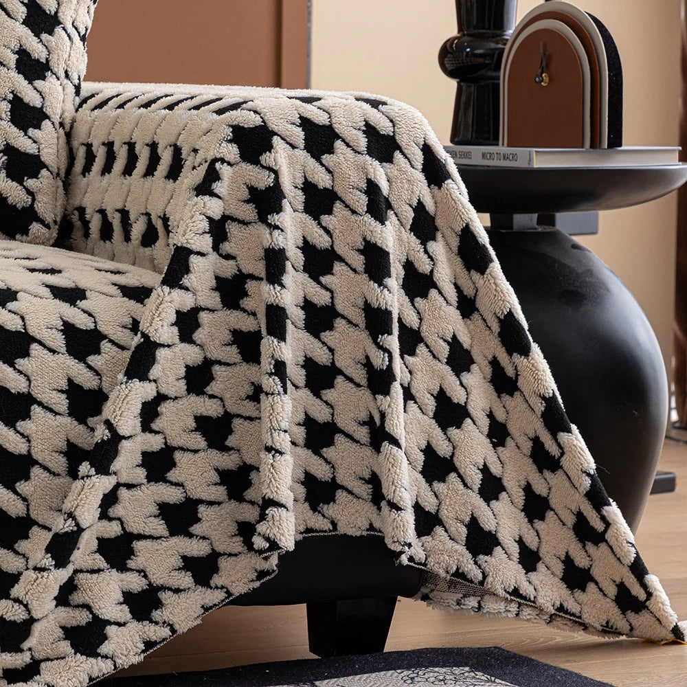 Black and white patterned blanket draped over a chair in a room with a vase and books on a table.