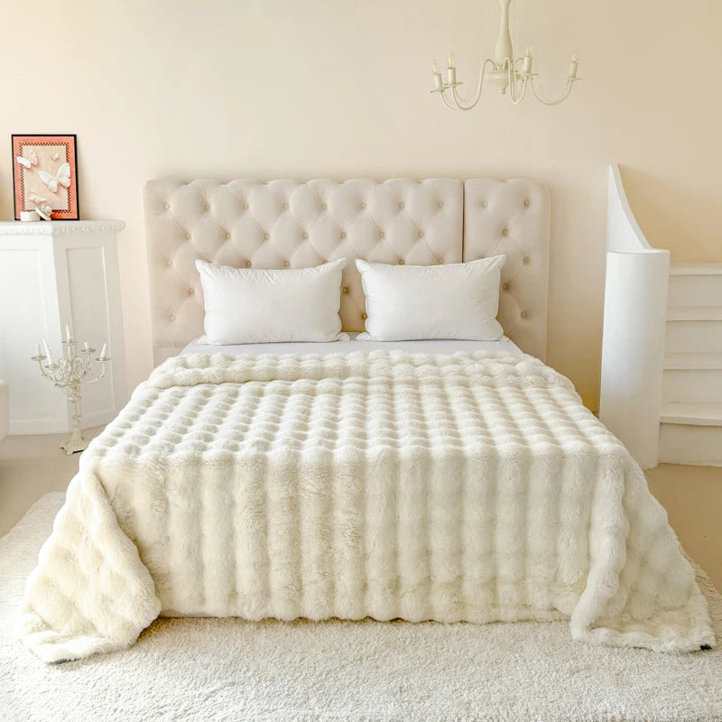 Bedroom with a bed covered in a white textured blanket and pillows.