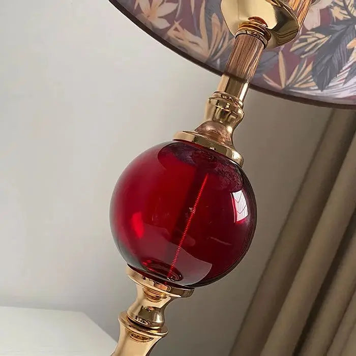 Close-up of a lamp with a red glass bulb and gold fixture.