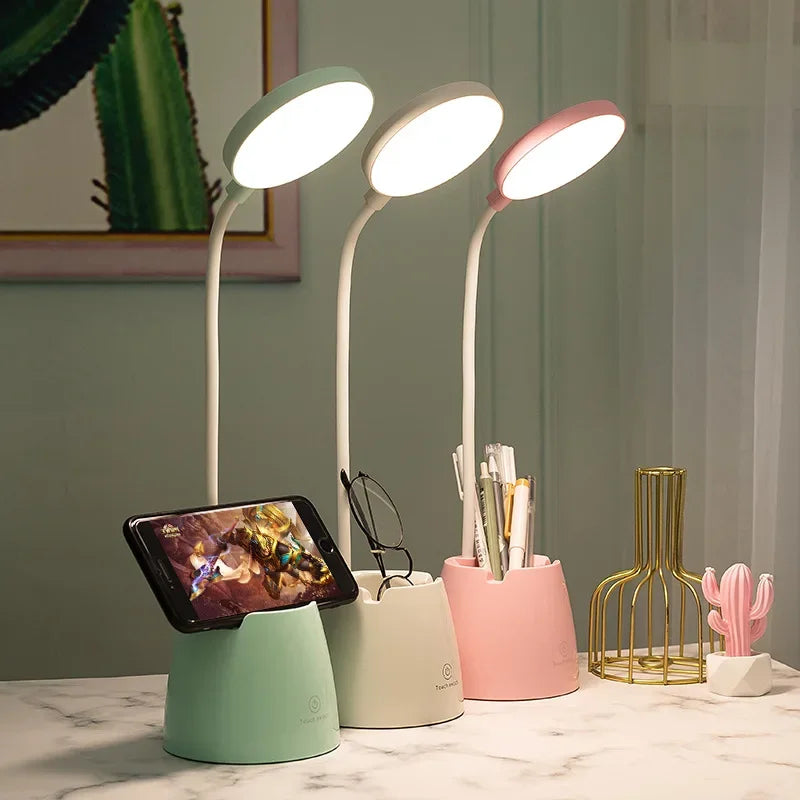 Three colourful desk lamps on a marble surface with a smartphone and small cactus decor.