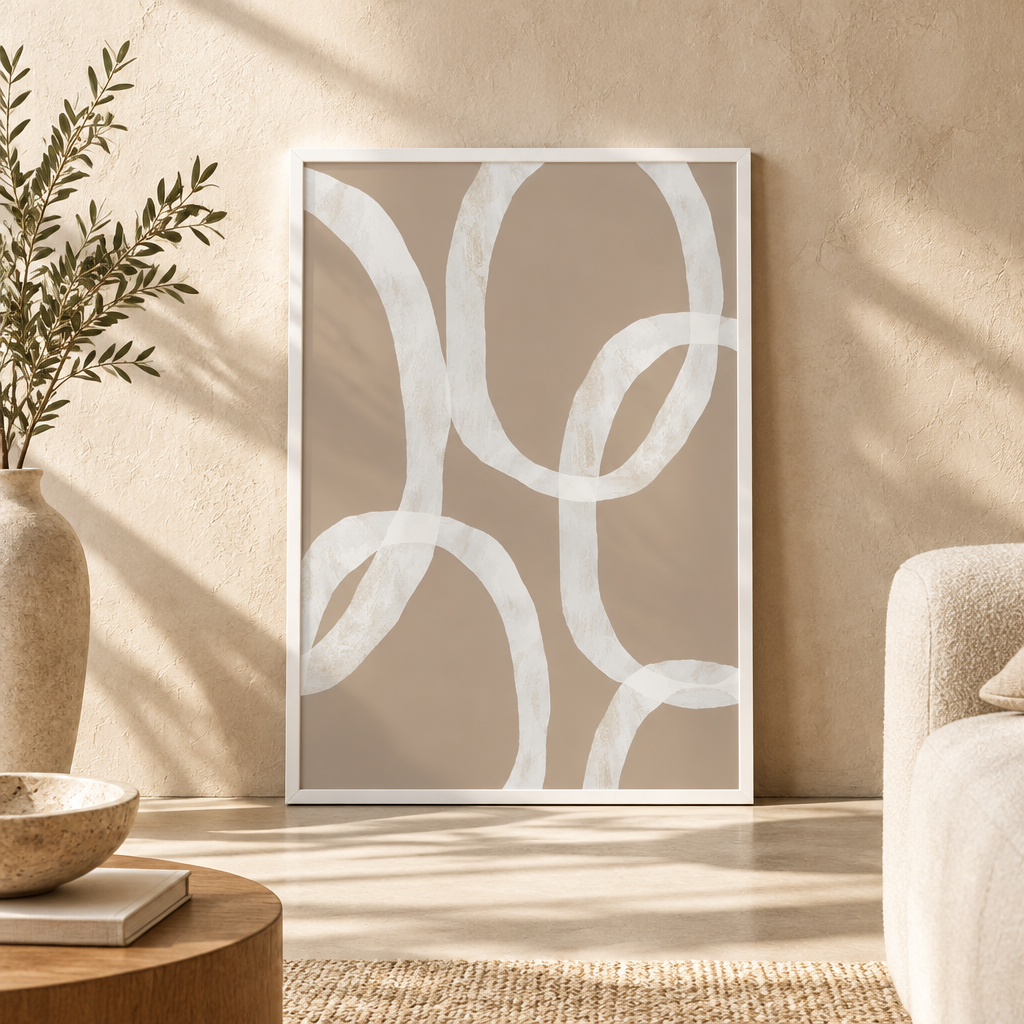 A framed abstract art print with white overlapping loop shapes on a warm taupe background, leaning against a textured beige wall in a styled interior setting.
